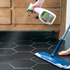 a person is cleaning the floor with a blue mop and a green sprayer