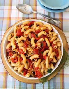 a white bowl filled with pasta and tomato sauce on top of a checkered table cloth