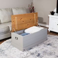 an open storage box sitting on top of a rug in front of a white couch