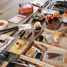 a wooden table topped with lots of art supplies