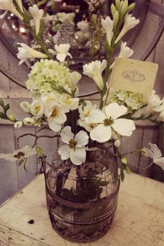 a vase filled with white flowers sitting on top of a table next to a mirror