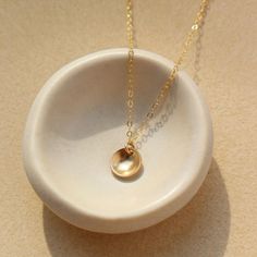 A small concave disc on a simple chain in 14k gold fill by token jewelry Dainty Brass Necklace With Round Pendant, Elegant Circle Hammered Necklaces, Elegant Hammered Circle Necklace, Dainty Tarnish Resistant Round Pendant Necklace, Dainty Round Pendant Necklace, Tarnish Resistant, Dainty Tarnish-resistant Round Pendant Necklace, Dainty Brass Charm Necklace With Round Pendant, Recycled Gold Charm Necklace With Round Pendant, Recycled Gold Round Pendant Charm Necklace