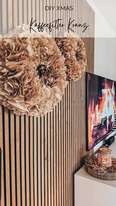 a tv sitting on top of a wooden table next to a wall with flowers hanging from it