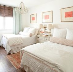 two beds in a bedroom with white linens and pink decor on the wall above them