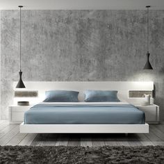 a bed with blue sheets and pillows in a room that has concrete walls on both sides