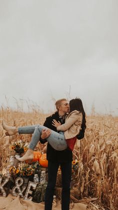 a man holding a woman in front of a corn field