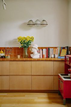 a vase filled with yellow flowers sitting on top of a wooden counter in a kitchen