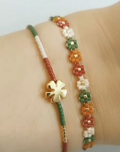 two bracelets that are on someone's arm, one with a clover and the other with beads