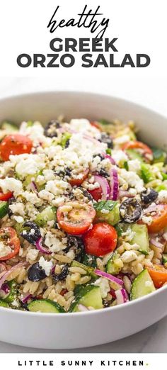 a salad with tomatoes, cucumber, olives and feta cheese in a white bowl