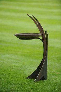 a metal sculpture sitting on top of a lush green field