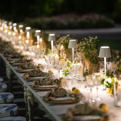 a long table is set up with candles and place settings for an outdoor dinner party