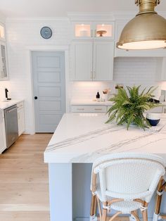 a kitchen with white cabinets and an island in the middle is lit by pendant lights