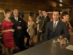 a group of people in suits and ties standing around a bar with drinks on it