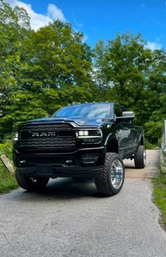 a black ram truck parked on the side of a road next to a wooded area