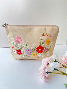 a small pouch with flowers on it and the word beba written in red, white, blue, yellow and pink