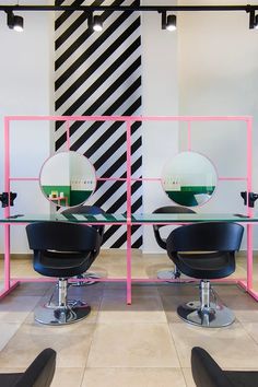 two salon chairs sitting in front of a glass table with mirrors on top of it