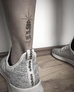 a woman's foot with a small lighthouse tattoo on her left side calf sleeve