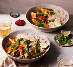 two bowls filled with rice, chicken and veggies next to glasses of beer