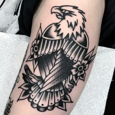 an eagle tattoo on the arm with flowers and leaves around it's neck, in black and white