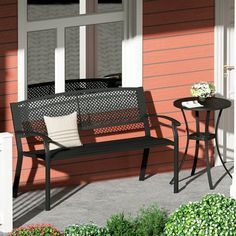 a black bench sitting on top of a patio next to a table with flowers in it