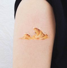 a woman's arm with a small wave painted on the back of her arm