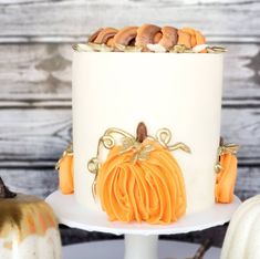 there is a white cake with orange frosting on the top and pumpkins around it