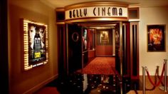 the entrance to a movie theater with red carpet and posters on the wall behind it