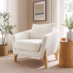 a living room with a white chair and potted plant on the floor next to it