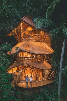 two people are standing on the roof of a tree house in the forest at night