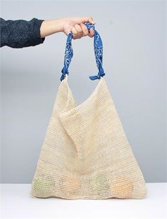 a person is holding a bag with a blue ribbon around it's handle and the handles are made out of jute