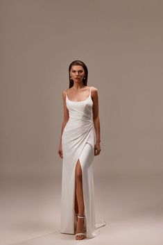 a woman wearing a white dress with a slit in the side and one leg up