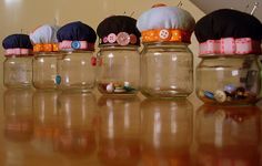 there are many jars with hats in them sitting on the table next to each other