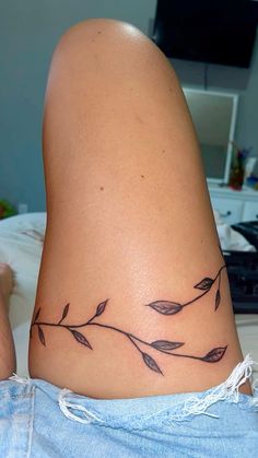 a woman's leg with a tattoo on it that has leaves growing out of it