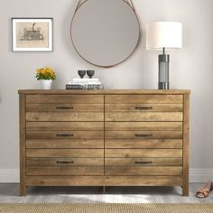 a wooden dresser with a round mirror above it