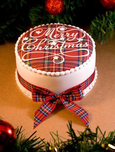 a decorated christmas cake sitting on top of a table next to a red ornament