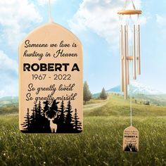 a personalized memorial wind chime in the grass with trees and mountains behind it