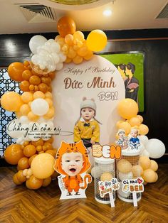 an orange and white birthday party with balloons, cake toppers, and photo frames