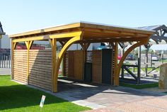 a small wooden shelter sitting on top of a green grass covered field next to a parking lot