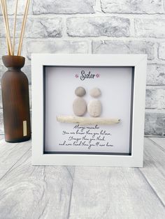 two rocks sitting on top of a wooden table next to a vase with reeds