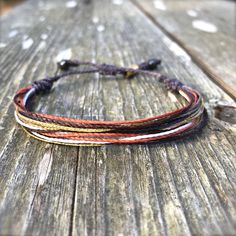 WOMENS WAXED CORD BRACELET: This hand-knotted multi-strand waxed cord bracelet includes two genuine Hematite stones and a Rumi Sumaq logo bead. In summer shades of muted violet purple, metallic gold, orange, brown and white it is the perfect beach accessory for surfers, sailors and beach lovers alike. Or you may think of this string bracelet as a sophisticated and grown up friendship bracelet. Buy one for yourself and another for your best friend. Or make it a sister's bracelet by purchasing one Brown Adjustable Cord Bracelet For Beach, Multicolor Waxed Cord Braided Bracelet For Beach, Purple Bohemian Bracelet With Adjustable Cord, Hand-strung Waxed Cord Bracelet Jewelry, Hand-strung Waxed Cord Bracelets For Beach, Mother Daughter Bracelet Set, Wax Cord Bracelet, Mother Daughter Bracelets, Summer Shades