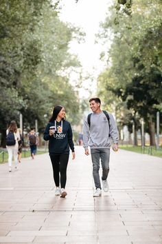 a man and woman walking down a sidewalk holding hands