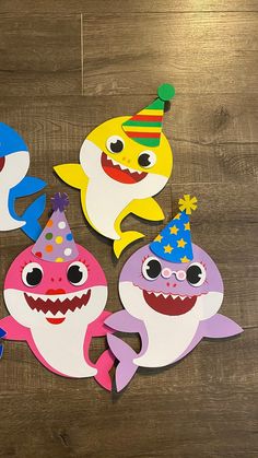 five shark cutouts with party hats on them sitting on a wooden table in front of a wood floor