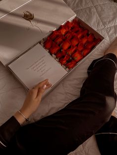 a person laying on a bed with a box of strawberries