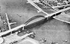 an aerial view of a bridge spanning the width of a body of water with boats in it