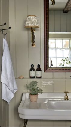 a white sink sitting under a bathroom mirror next to a wooden framed mirror above it