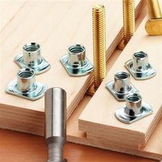 screws and nuts are placed on top of a piece of wood with two holes in the middle