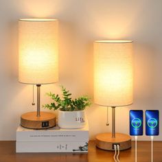 two lamps sitting on top of a wooden table next to a box with an electronic device