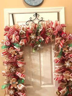 a christmas wreath with candy canes and ornaments hanging on the front door to welcome guests