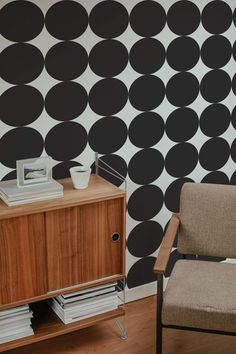 a living room with black and white polka dot wallpaper, a chair and side table