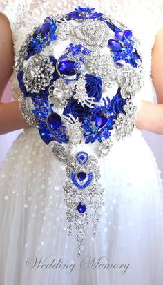 the bride's bouquet is made up of blue and silver brooches, which are embellished with jewels